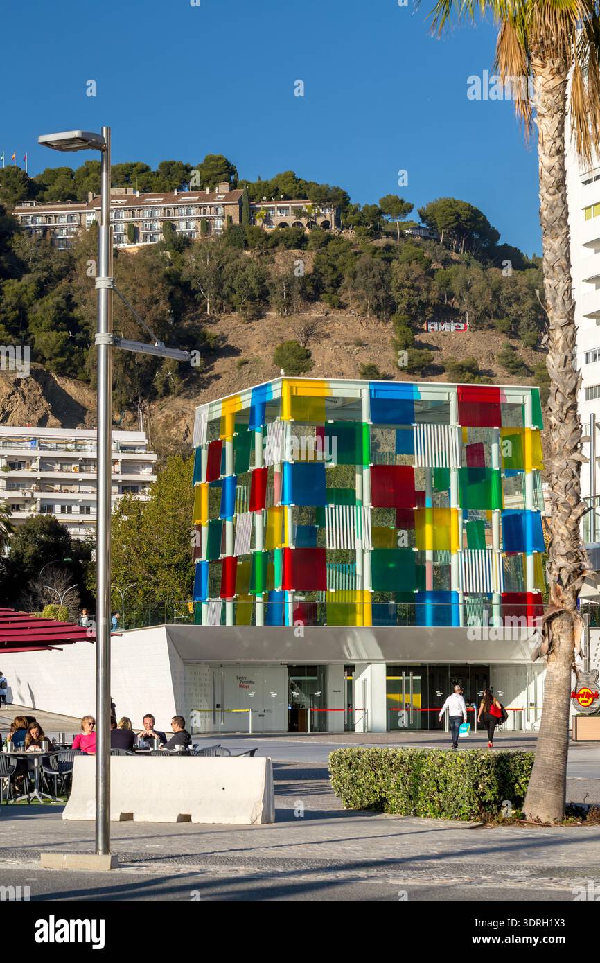 Malaga, Espagne – 10 février 2020 : le cube de verre coloré du musée du Centre Pompidou se dresse devant la colline Gibralfaro avec les murs historiques du château Banque D'Images