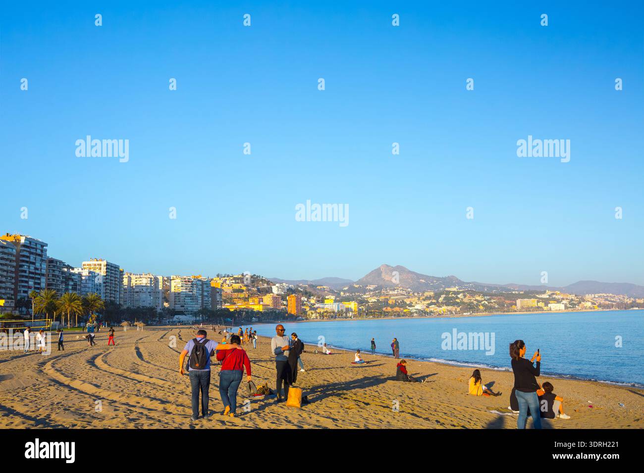 Malaga, Espagne – 10 février 2020 : les familles et les touristes profitent du soleil sur la plage de la Malagueta avec des immeubles résidentiels de grande hauteur et un ensemble de filets de volley-ball Banque D'Images