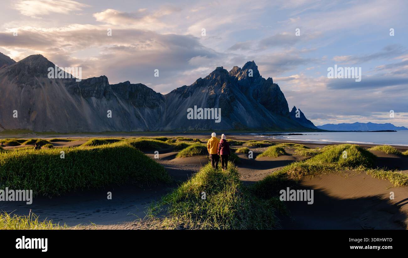 Vue imprenable sur la montagne Vestrahorn avec des randonneurs sur les dunes de sable noir dans le paysage serein islandais Banque D'Images
