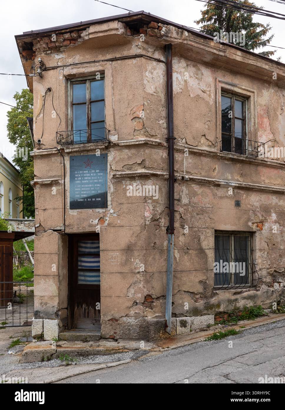 Travnik, Bosnie-Herzégovine - 24 août 2022 : façade d'un ancien bâtiment montrant du béton altéré et une plaque commémorative en étoile rouge à Travnik. Banque D'Images