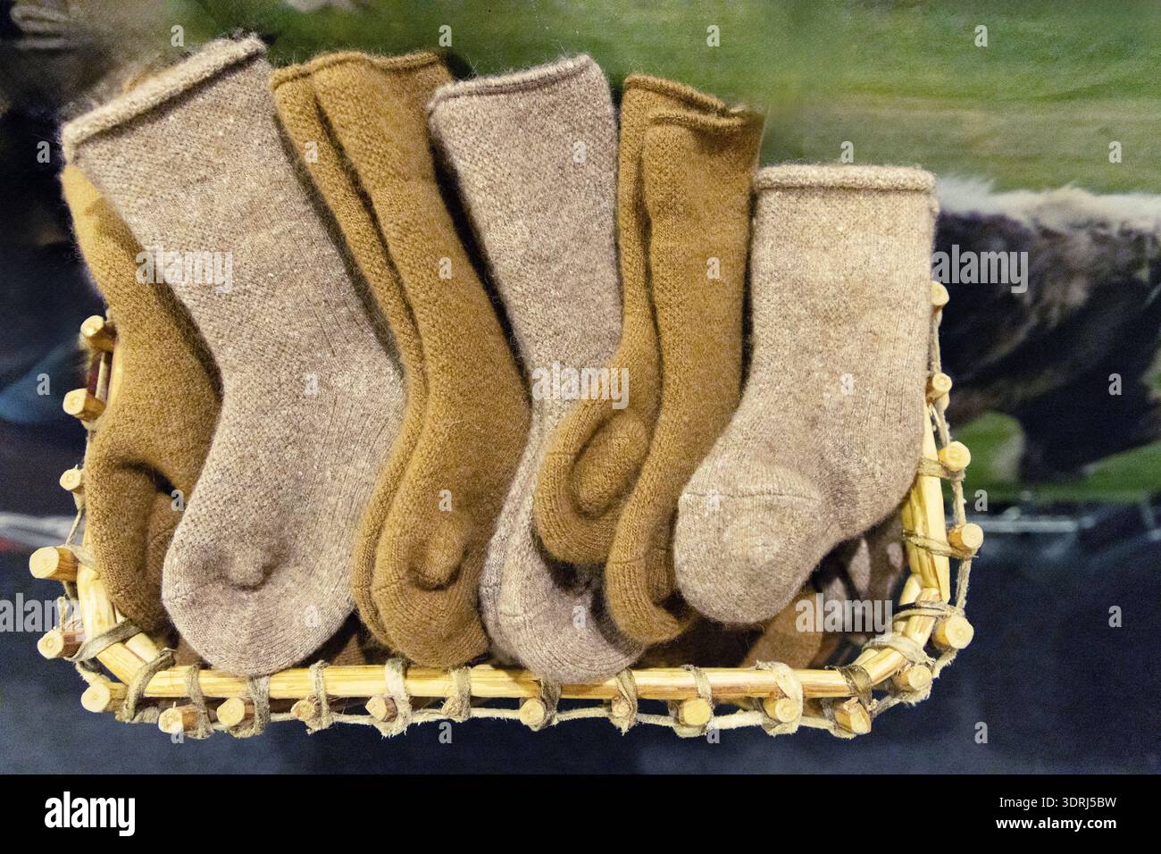 Chaussettes en laine confortables disposées soigneusement dans un panier tissé présentant des textures naturelles et des couleurs chaudes Banque D'Images
