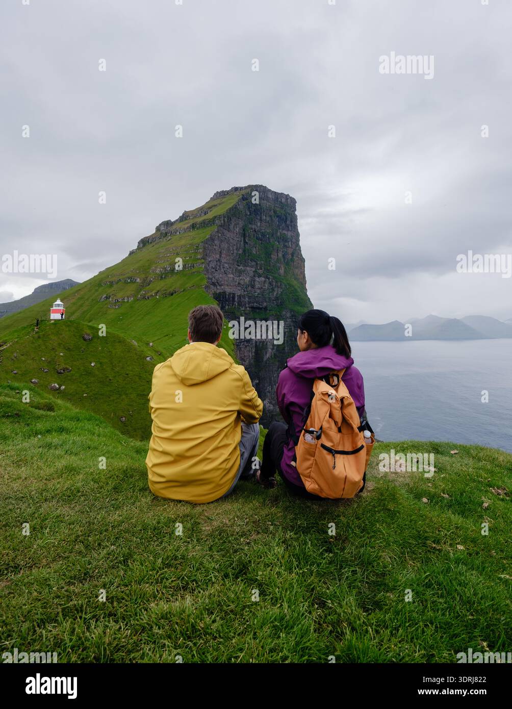 Vue imprenable sur les randonneurs surplombant les falaises majestueuses des îles Féroé par temps nuageux Banque D'Images