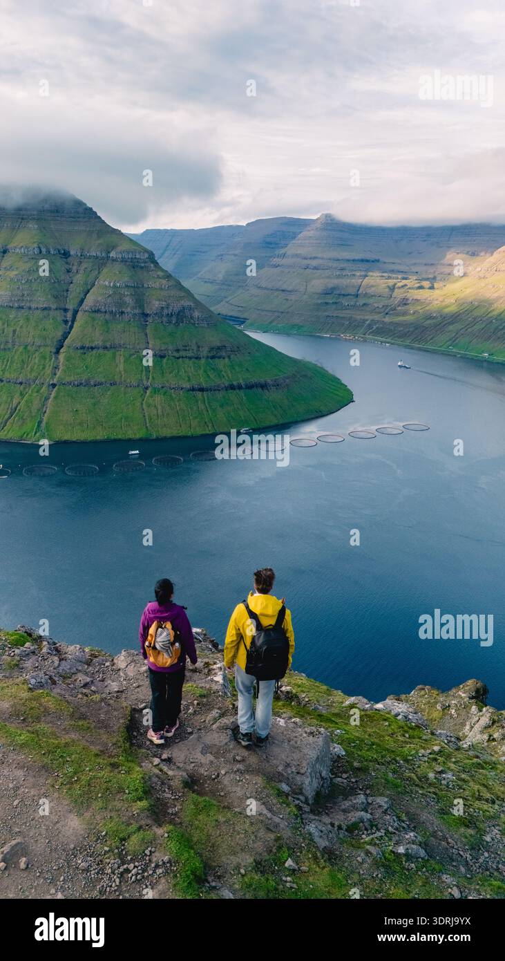 Découvrez des vues à couper le souffle sur les îles Féroé avec des randonneurs surplombant un paysage luxuriant Banque D'Images