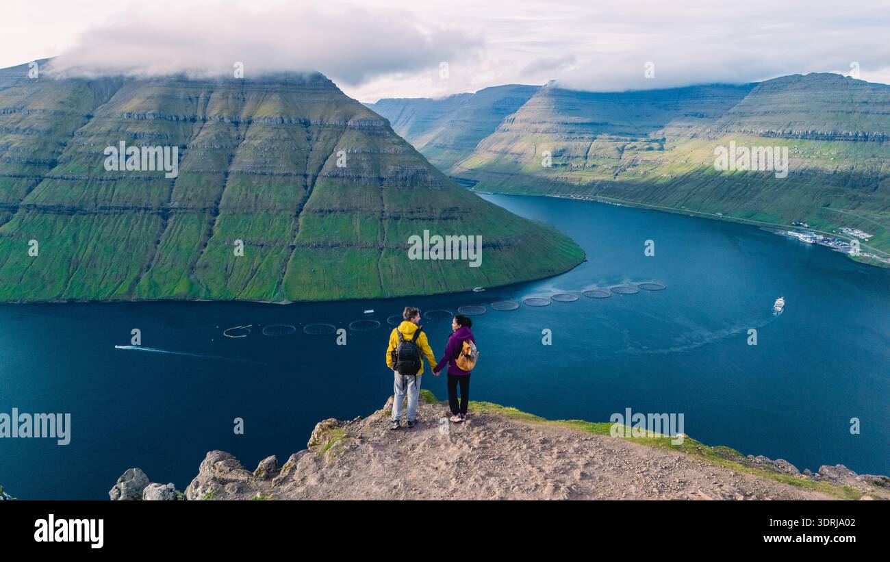 Vue imprenable sur les randonneurs surplombant le magnifique paysage des îles Féroé au lever du soleil Banque D'Images