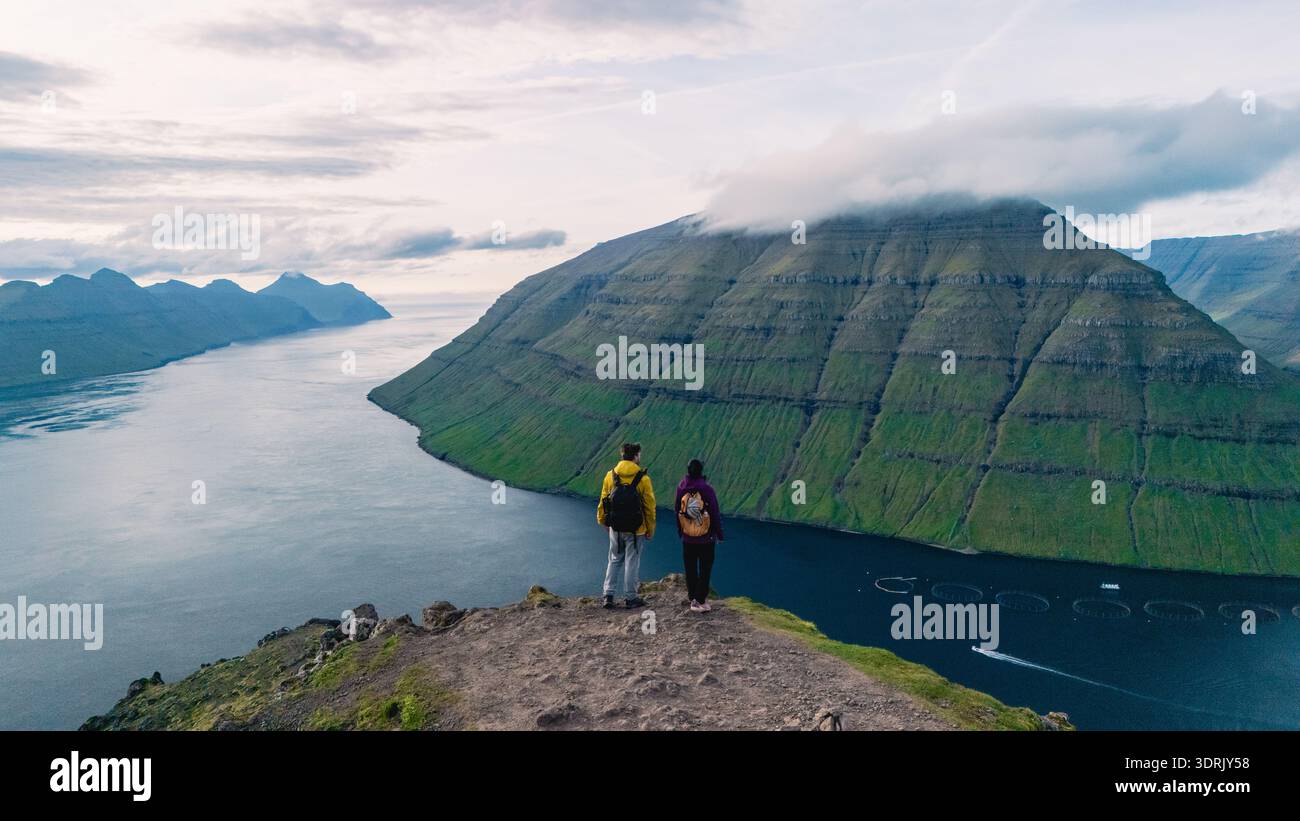 Vue panoramique des randonneurs surplombant le paysage spectaculaire des îles Féroé avec des collines verdoyantes Banque D'Images