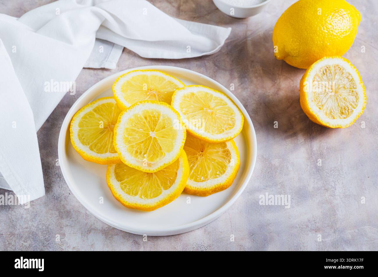 Citrons coupés en tranches juteuses dans une assiette et entiers sur la table Banque D'Images