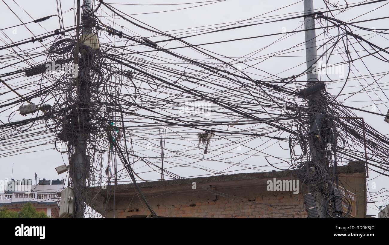 Réseau complexe de fils électriques aériens et poteaux électriques dans un environnement urbain. Banque D'Images