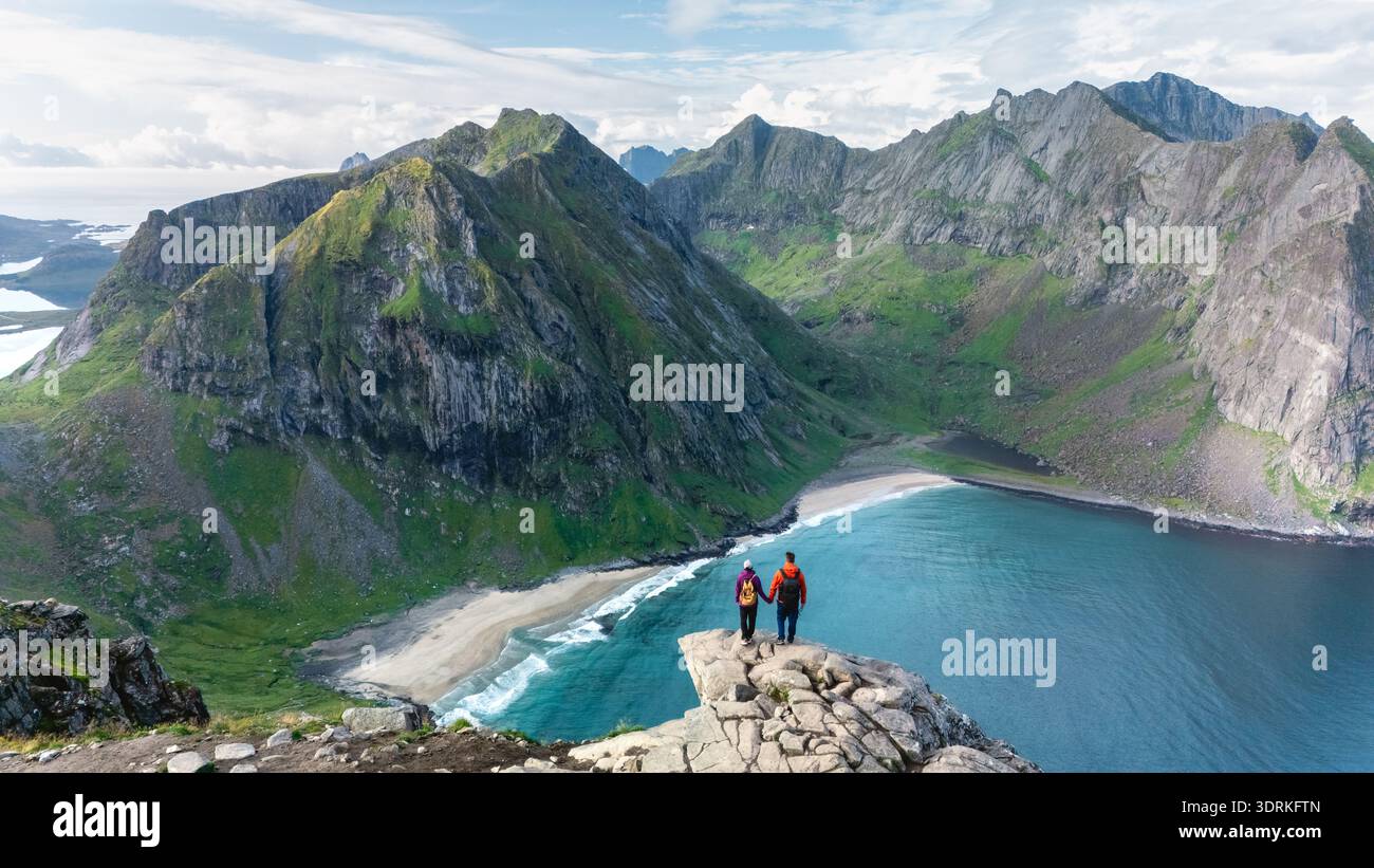 Les randonneurs se tiennent sur une corniche rocheuse, contemplant le paysage époustouflant de la plage de Ryten Kvalvika Banque D'Images