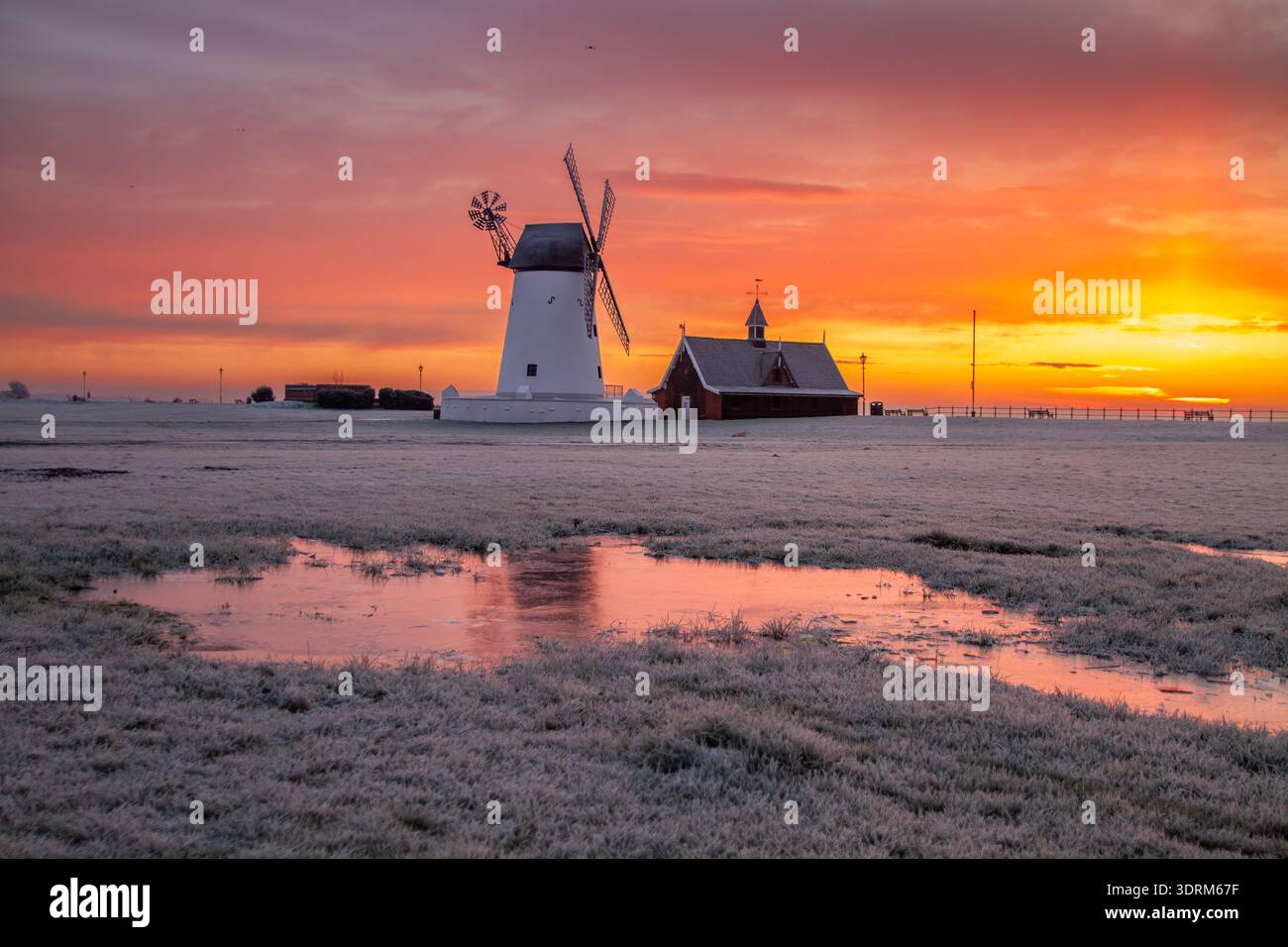 Lever de soleil givré au moulin à vent de Lytham, Lytham St Annes, avec le ciel brillant reflété dans les flaques d'hiver. Banque D'Images