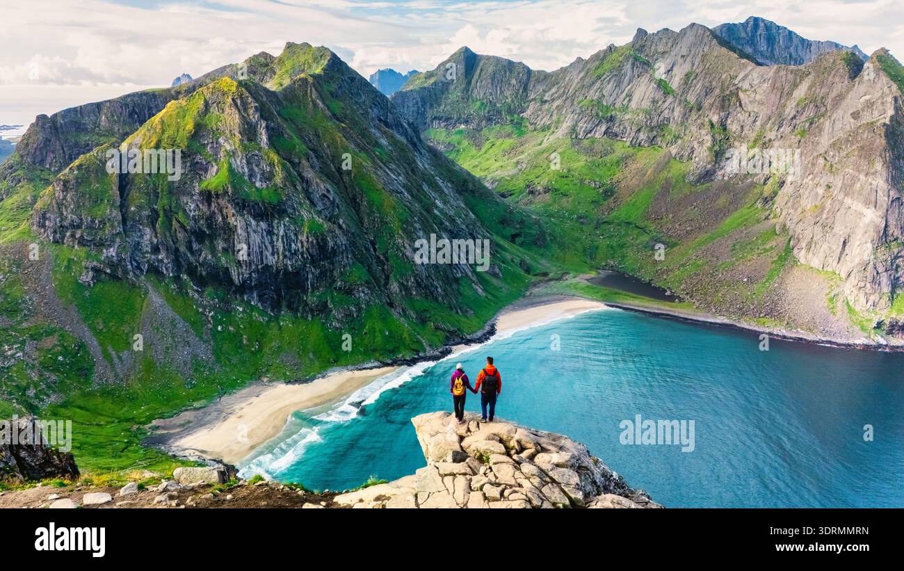 Deux randonneurs admirent le magnifique paysage depuis le pic Ryten, en contemplant les eaux turquoises de la plage de Kvalvika. Ce m inoubliable Banque D'Images