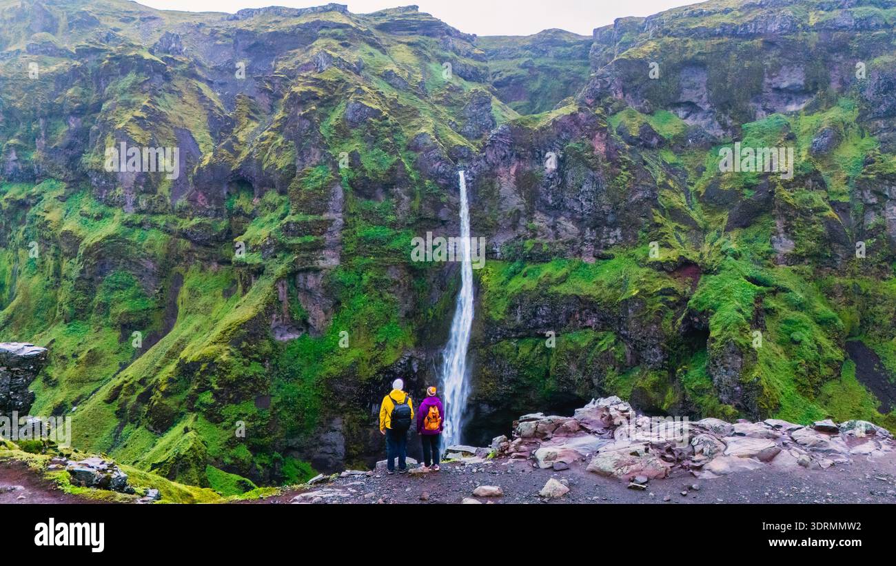 Deux aventuriers admirent le canyon à couper le souffle de Mulagljufur en Islande, devant une cascade spectaculaire qui descend en cascade Banque D'Images