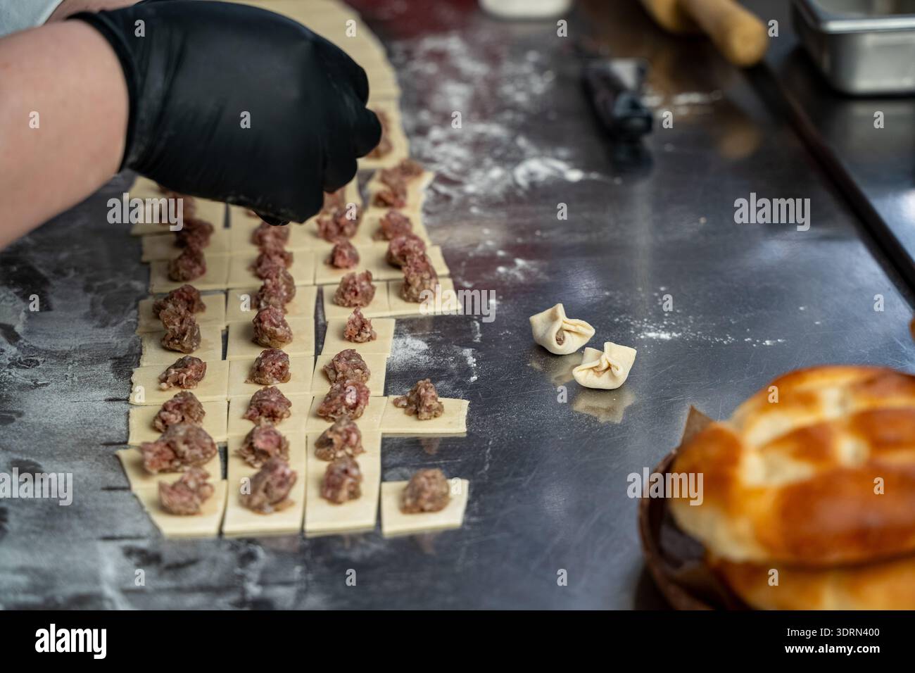 Gros plan du chef façonnant des morceaux de pâte fourrés sur le comptoir. Banque D'Images