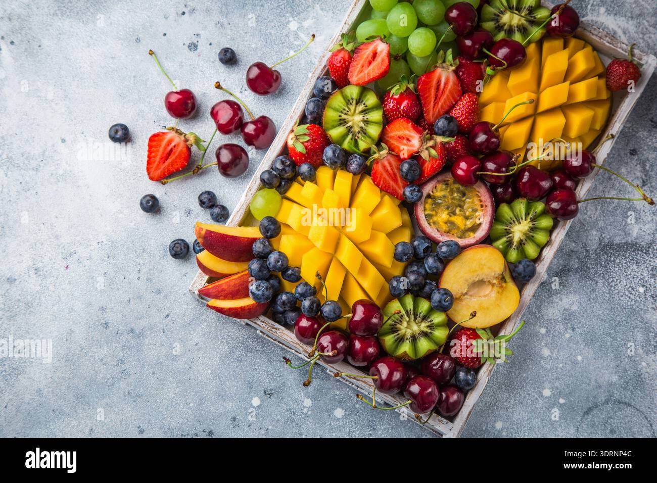Délicieux plateau de fruits et de baies. Mangue, kiwi, fraise, raisin, cerise, myrtille, pêche et fruit de la passion Banque D'Images