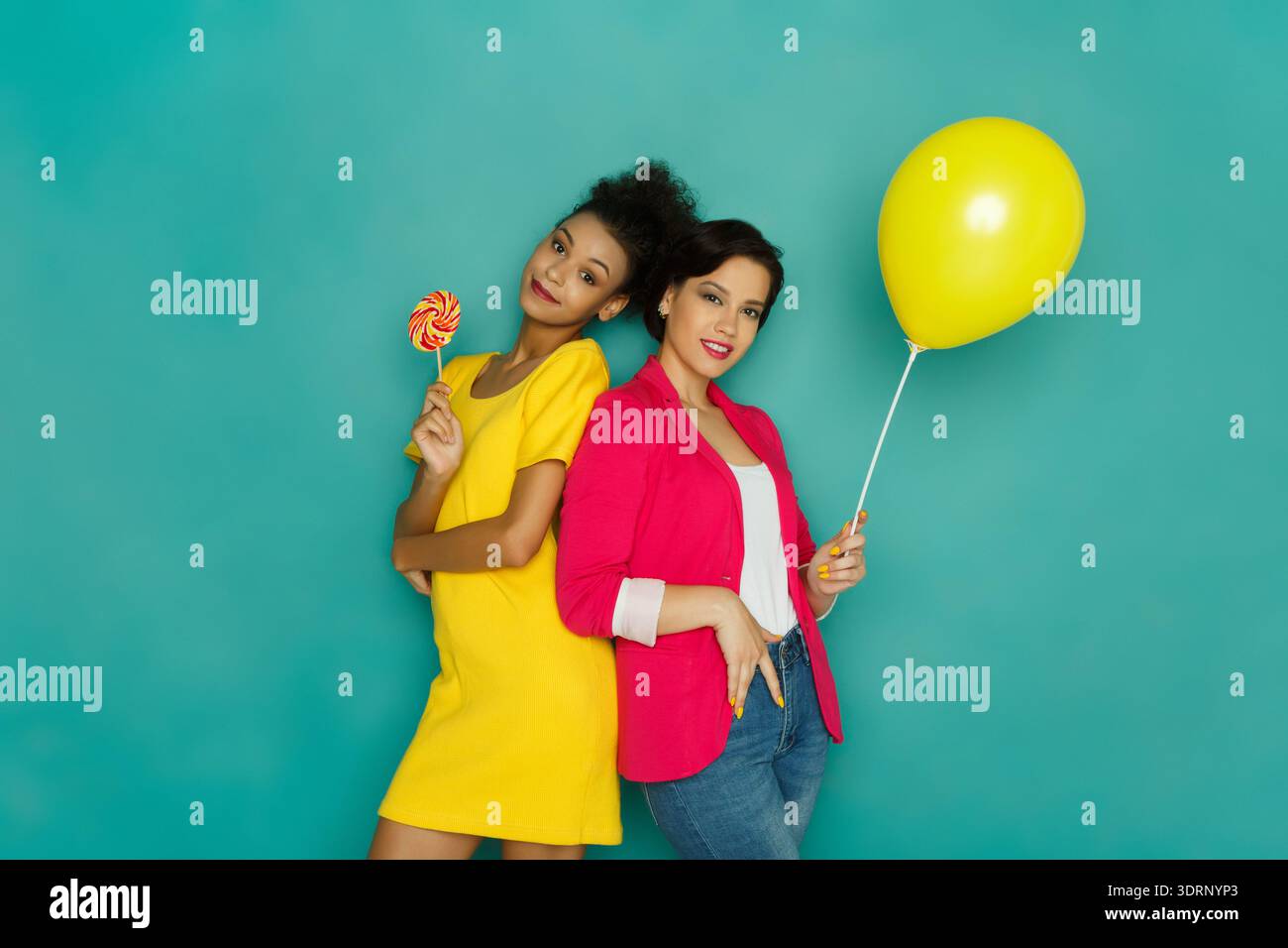 Les amis s'amusent avec Candy et un ballon dans un cadre coloré Banque D'Images