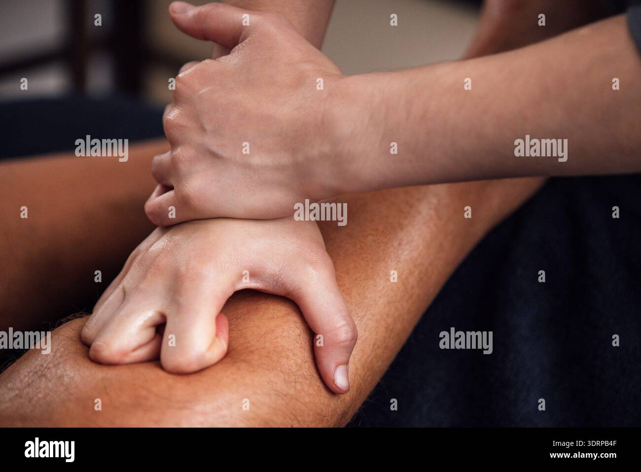 Massothérapeute professionnel appliquant la technique des tissus profonds sur la jambe d'un client, mettant en valeur la relaxation et le bien-être dans un cadre serein Banque D'Images