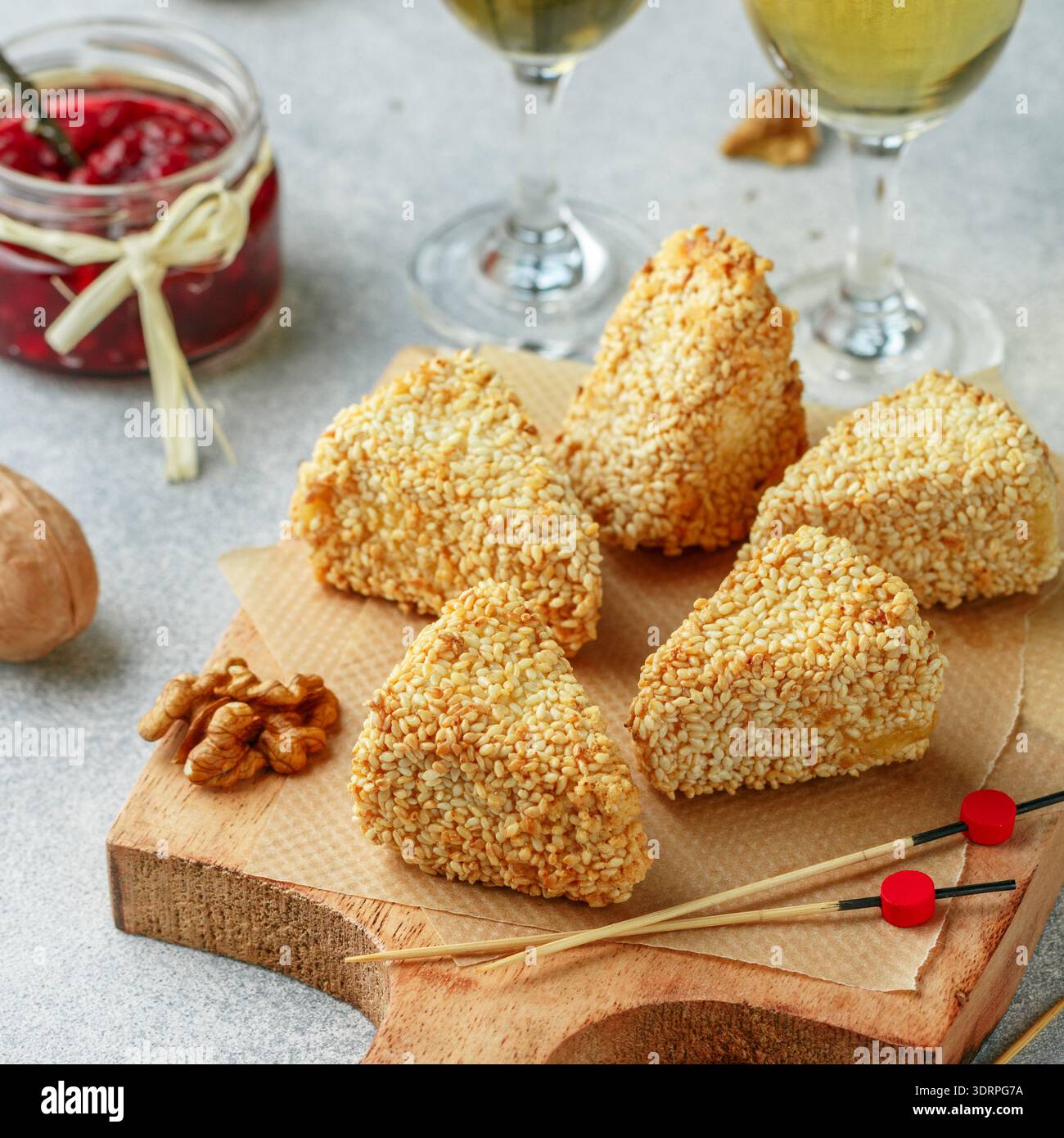 Camembert ou brie grillé ou cuit au four. Hors-d'œuvre délicat en panure de sésame avec vin. Servi avec noix et cranberr Banque D'Images
