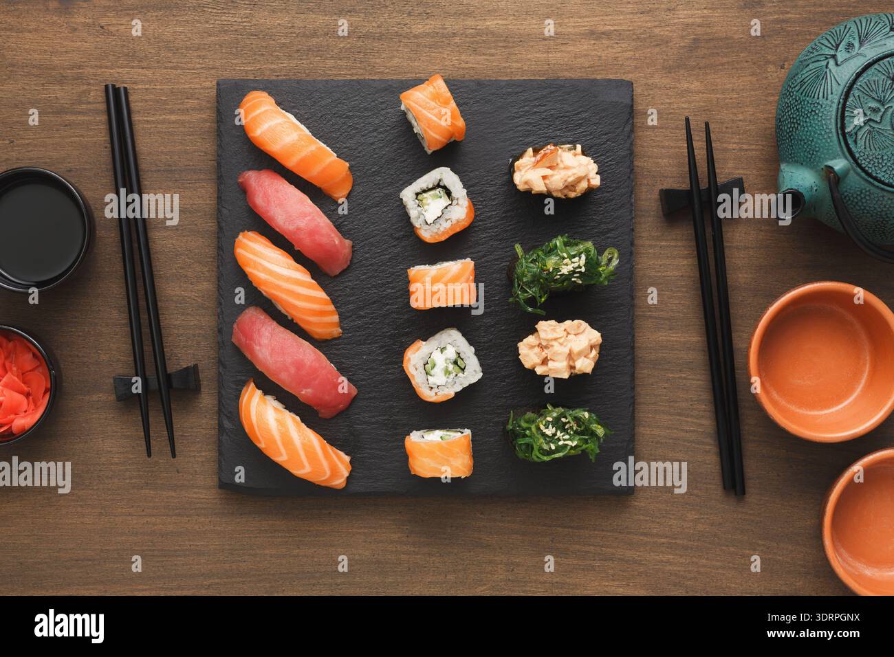 Plateau à sushis servi sur un plateau en pierre noire avec baguettes et thé dans un cadre de style japonais Banque D'Images