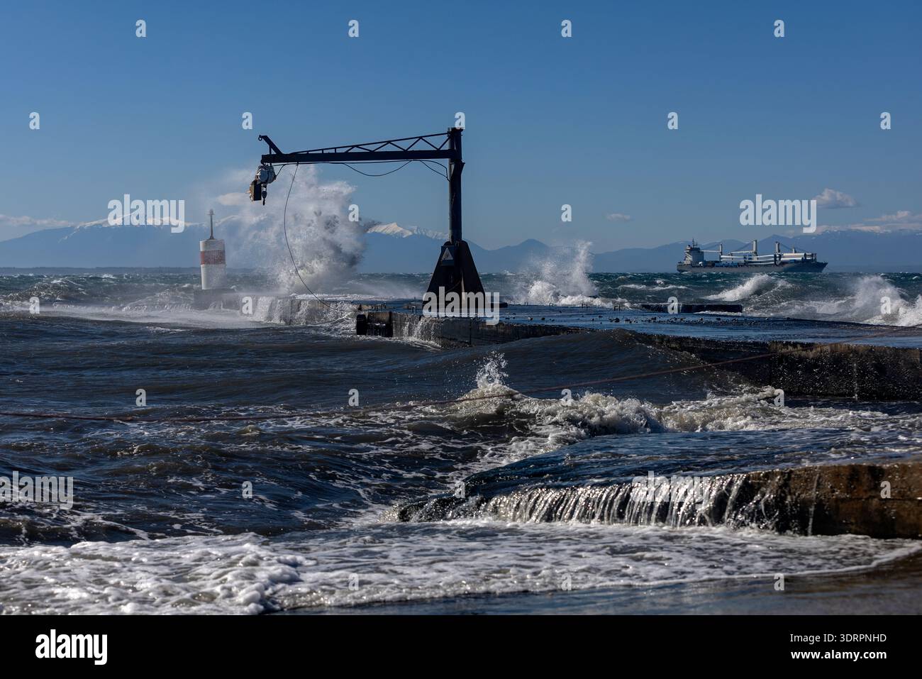 Une collection de photographies côtières spectaculaires montrant un cargo naviguant sur une mer agitée, de puissantes vagues s'écrasant contre une jetée en béton et un méta Banque D'Images