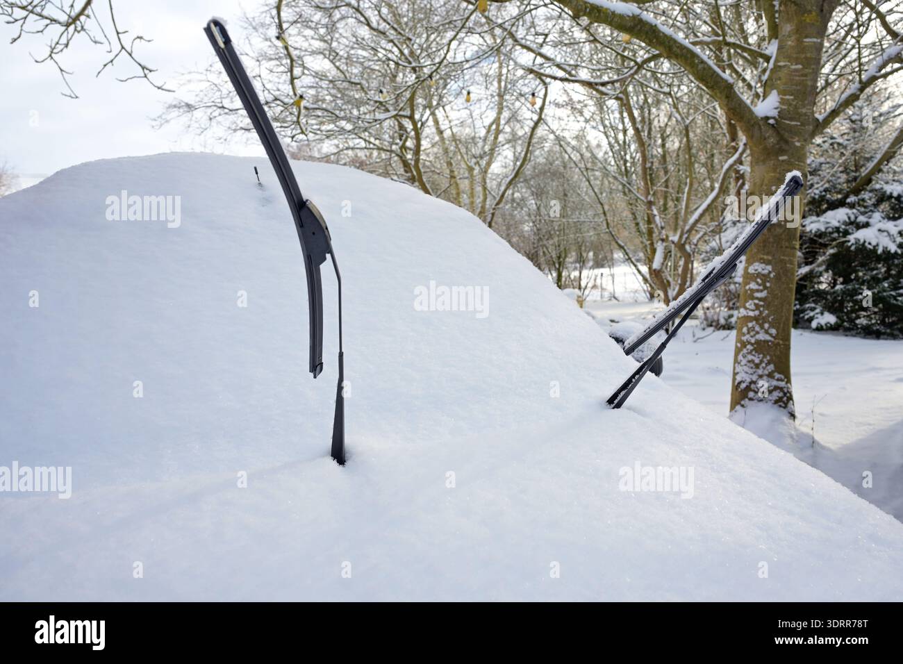 Voiture enneigée avec essuie-glaces surélevés pour les empêcher de geler sur le pare-brise, problèmes de circulation et de transport dans la saison froide d'hiver, co Banque D'Images
