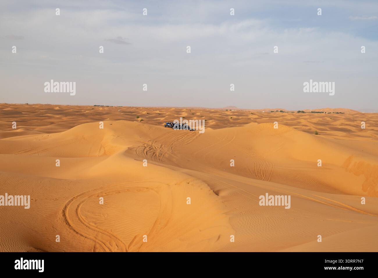 Dunes de sable ondulées avec des quad au loin dans le désert de Rub al Khali Banque D'Images