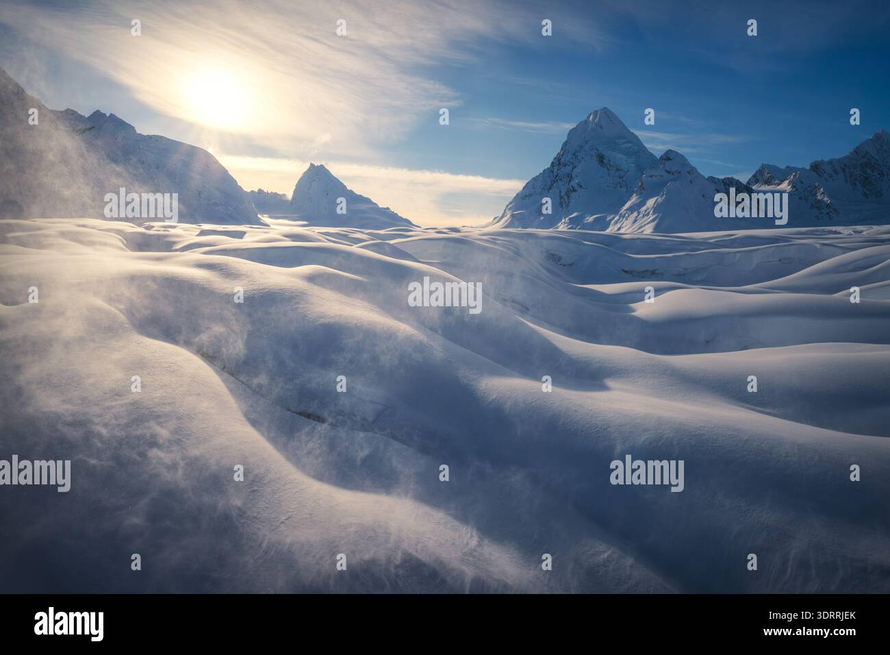 Vue aérienne d'un paysage de neige balayé par le vent, où des rafales glacées sculptent les dérives en formes fluides sous le regard vigilant des sommets enneigés, Valdez, Alask Banque D'Images