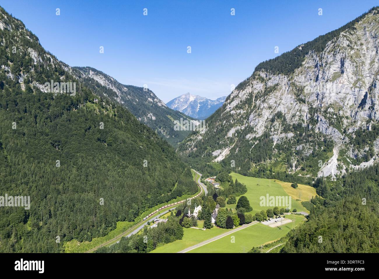 Vue aérienne d'une vallée verdoyante entourée de montagnes imposantes, où les ombres dansent avec la lumière du soleil, Wildalpen, Styrie, Autriche. Banque D'Images