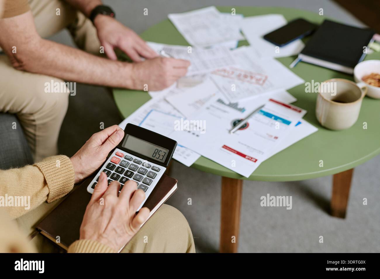 Femme caucasienne senior utilisant la calculatrice lors de l'examen des documents financiers Banque D'Images