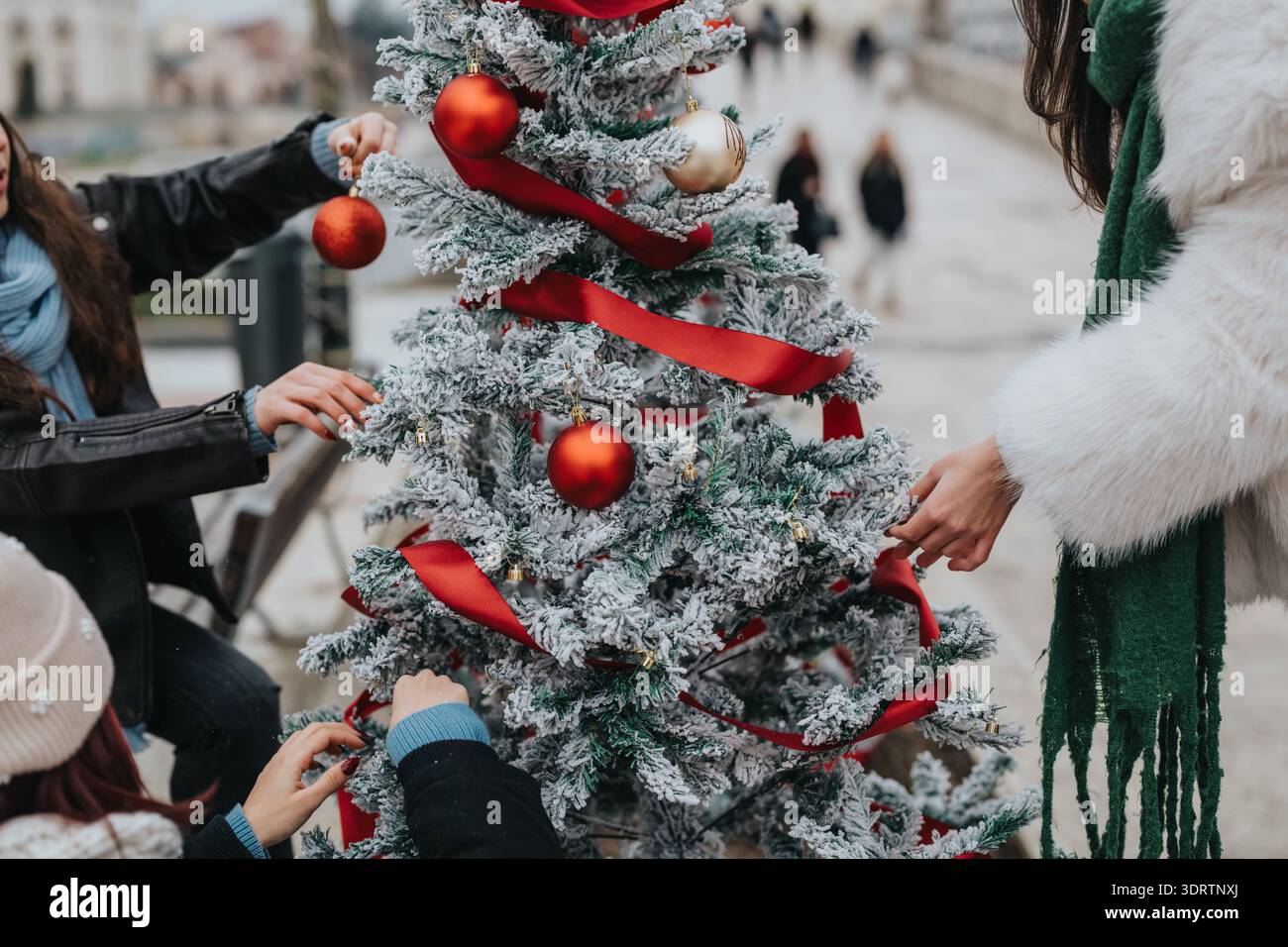 Les filles décorent un arbre de Noël givré avec des rubans rouges et des ornements dans une scène festive Banque D'Images