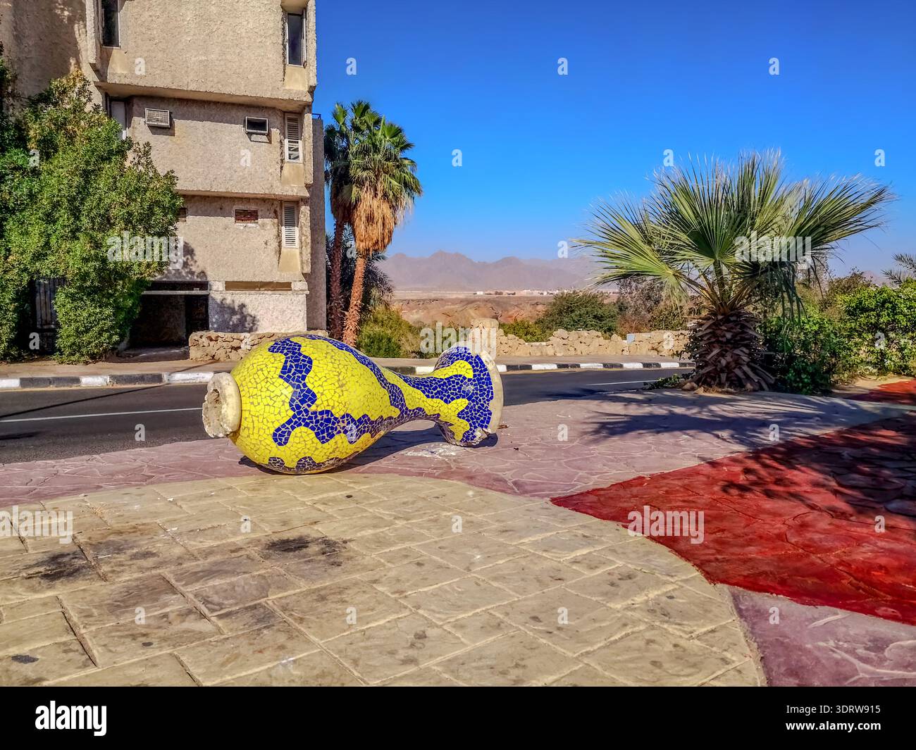 Une cruche en mosaïque jaune et bleue se trouve sur le trottoir à Charm el-Cheikh (Egypte). Décoration de rue avec des bols dans une ville touristique égyptienne - Image de stock capturée avec un smartphone
