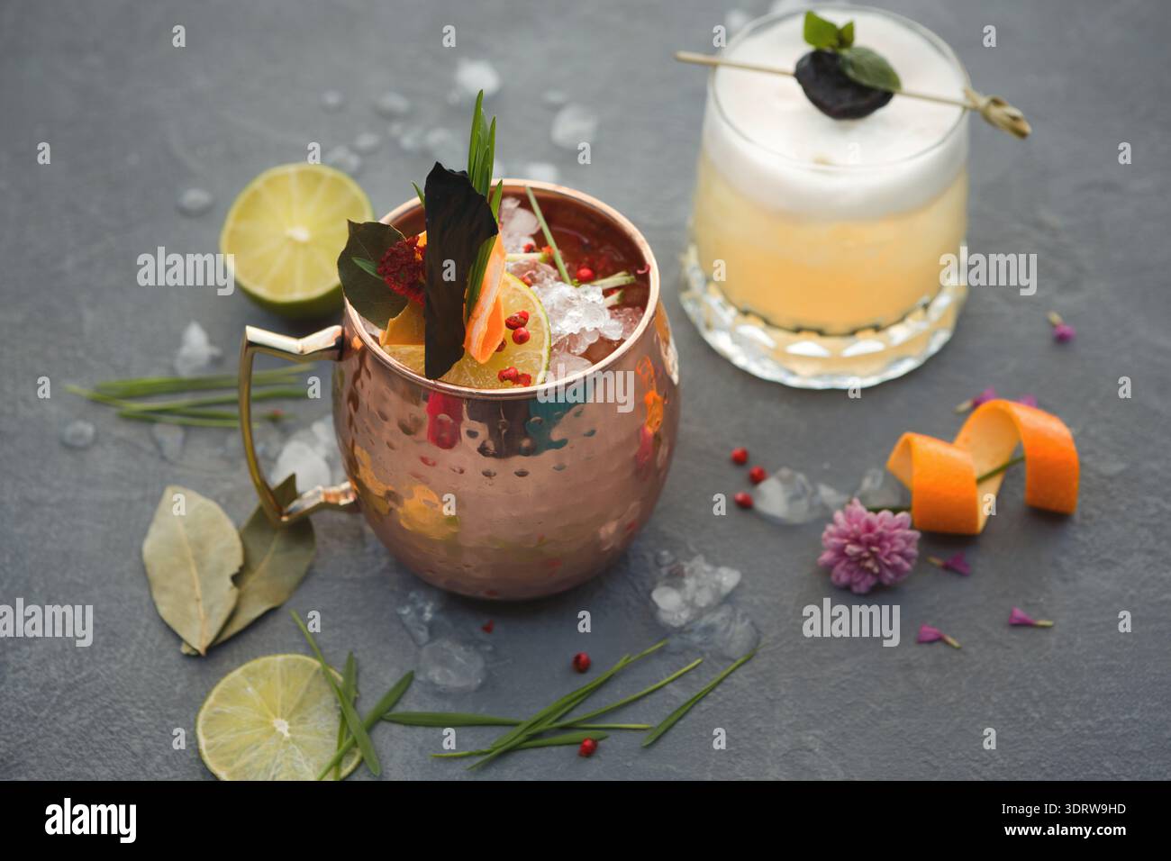 Cocktails servis dans des verres uniques avec garnitures et glace sur une surface grise Banque D'Images