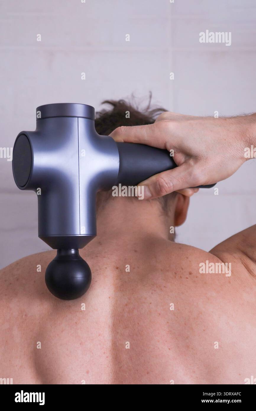 Plan détaillé d'un masseur à percussion travaillant sur le haut du dos et la région du cou, soulageant les tensions musculaires Banque D'Images
