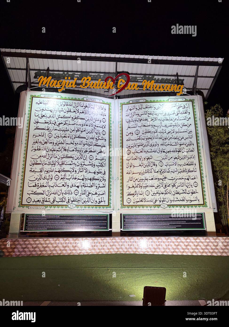 Kelantan, Malaisie - 7 février 2026. Une grande page d'affichage du Coran avec écriture arabe illuminée et traductions malaises sous la lumière de la nuit - Image de stock capturée avec un smartphone