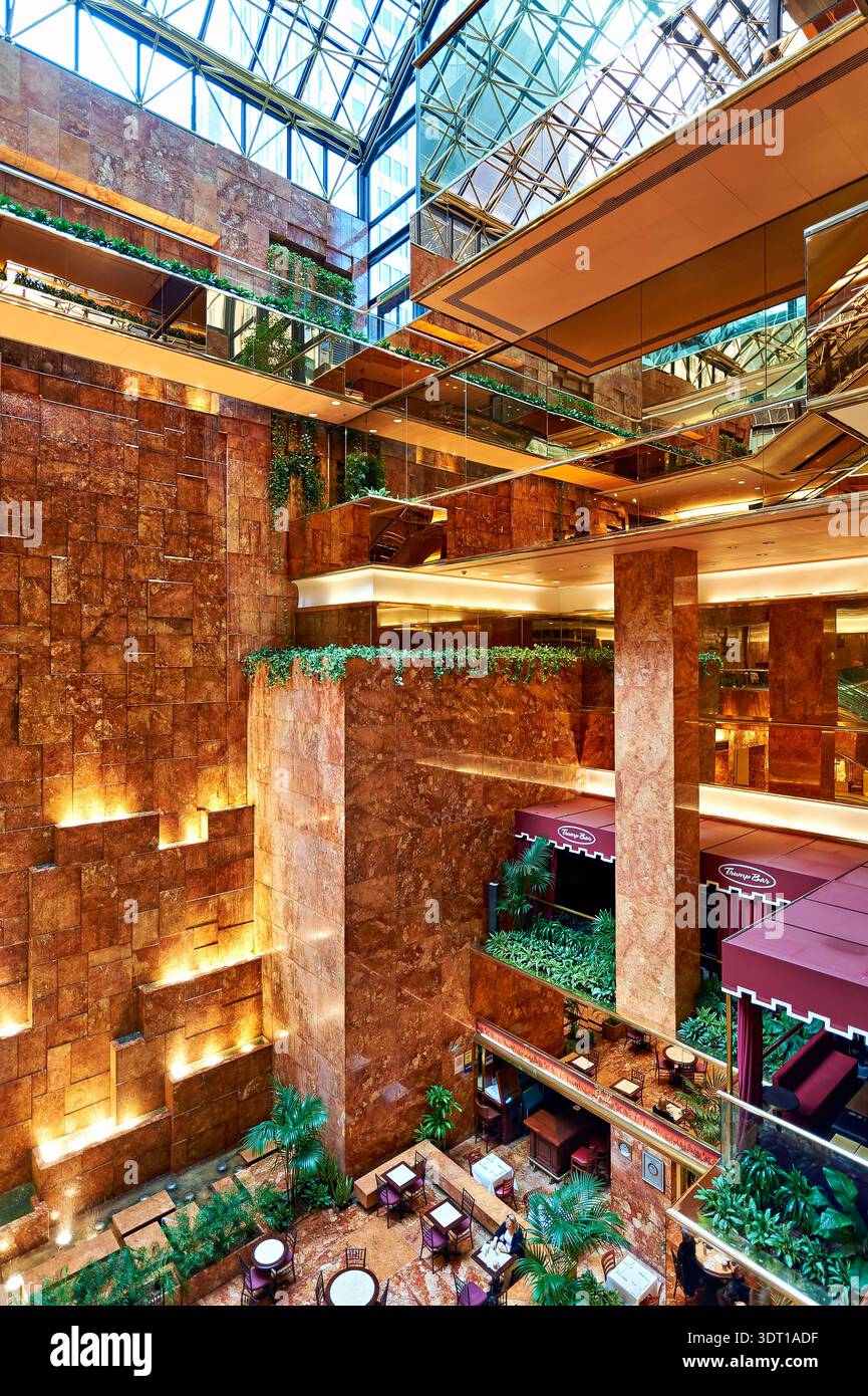 Les visiteurs explorent le Trump Tower Atrium à Manhattan, appréciant le design moderne et l'aménagement spacieux pendant un après-midi chargé. Banque D'Images