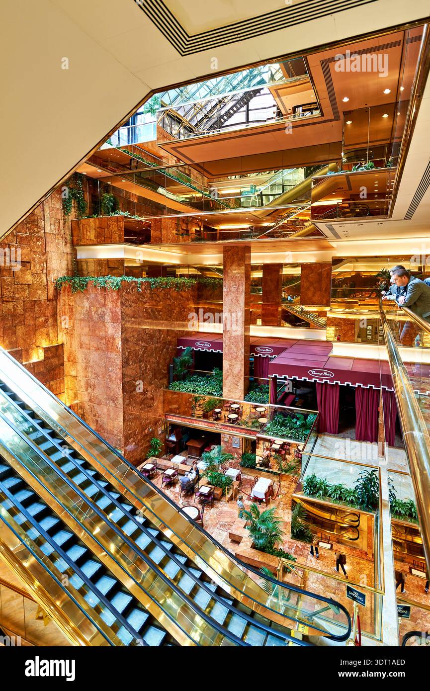 Les gens marchent dans l'atrium Trump Tower à Manhattan. Le grand espace présente des détails en verre et en marbre, avec des boutiques et des coins salon. Banque D'Images