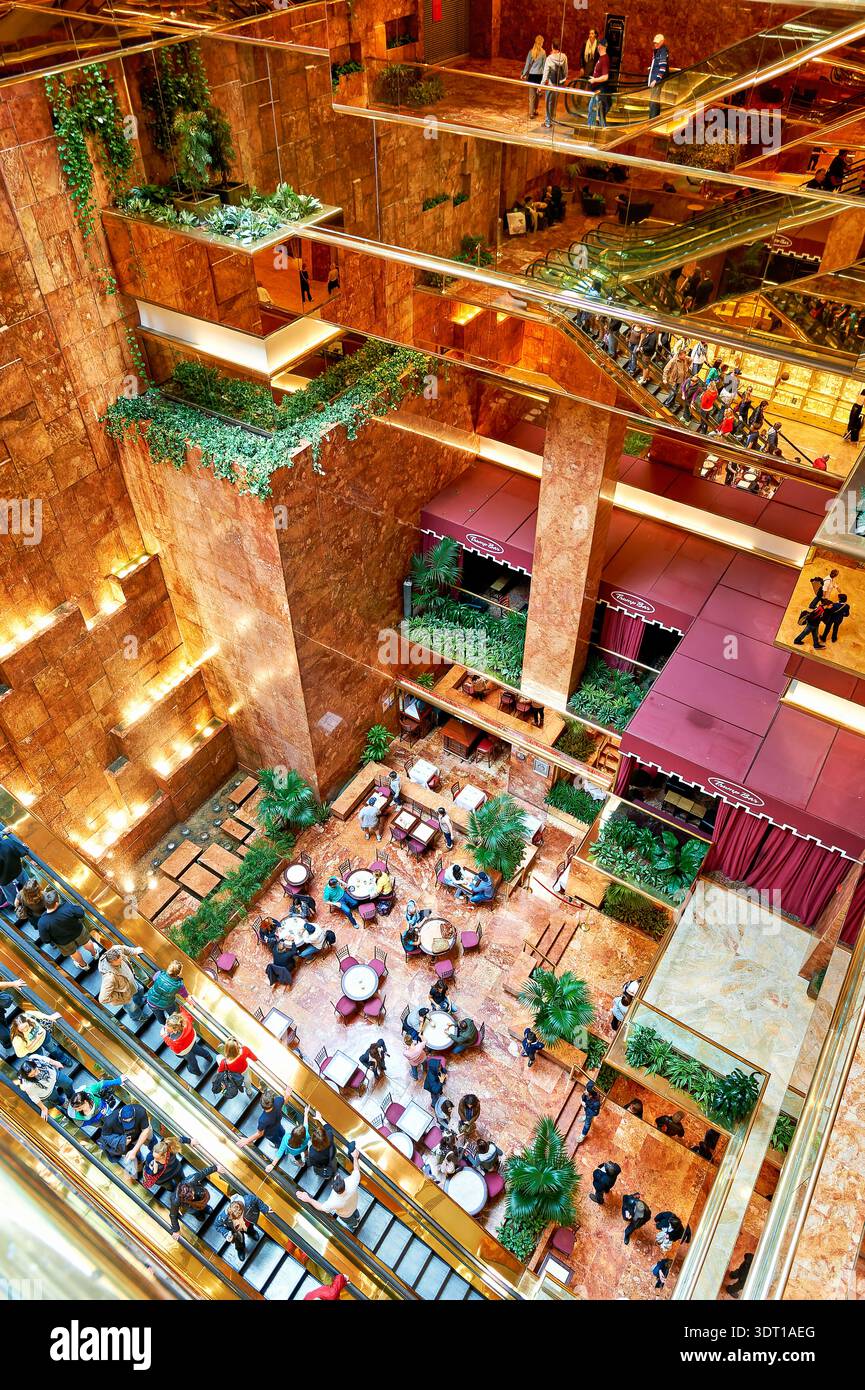 Les gens marchent et s'assoient dans l'atrium de la Trump Tower à Manhattan, New York. L'atrium dispose de sièges, de plantes et de plusieurs niveaux. Banque D'Images