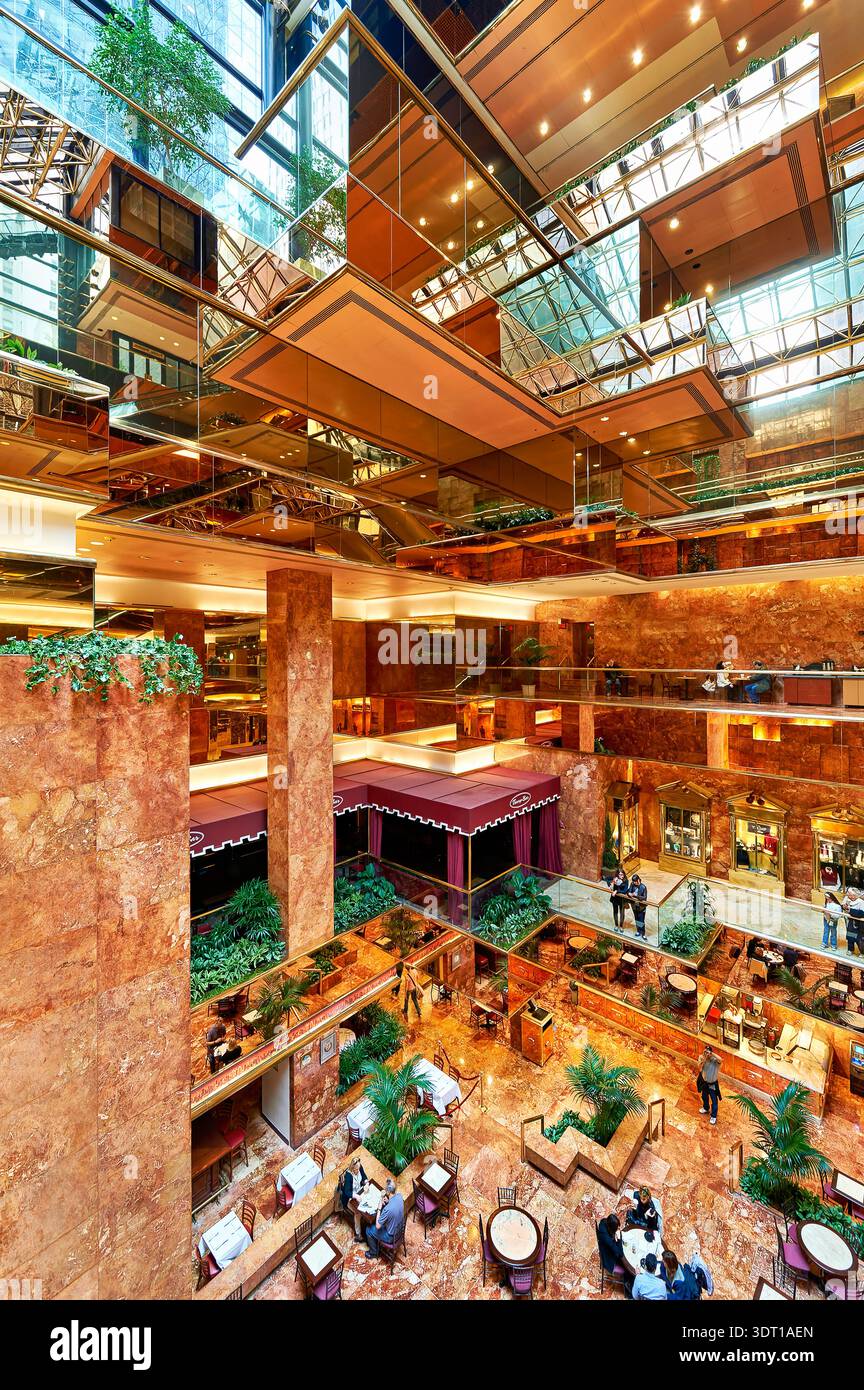 Les gens se promènent dans l'atrium Trump Tower tout en appréciant le design intérieur et les hauts plafonds en verre. Les plantes ajoutent à l'atmosphère. Banque D'Images