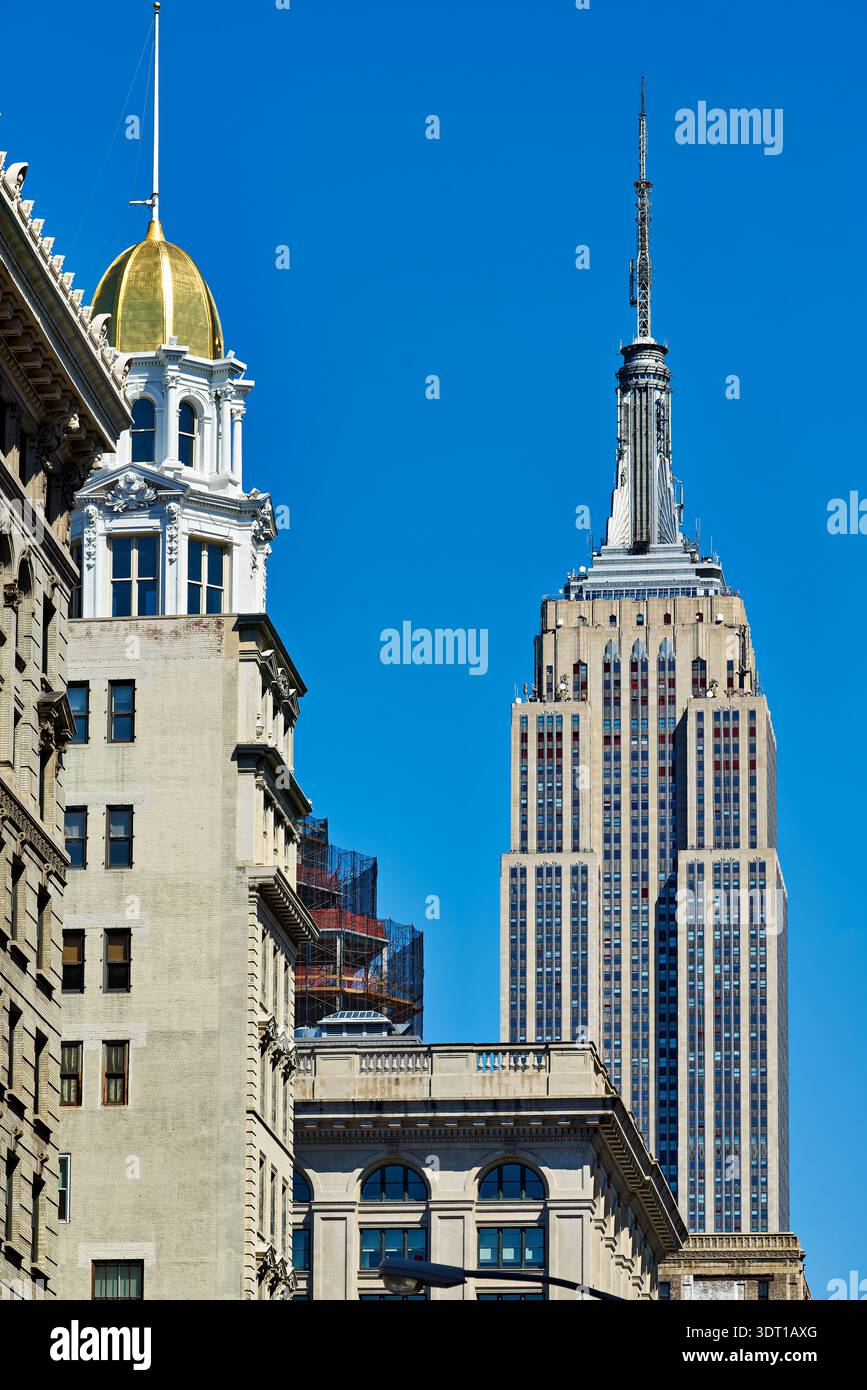 L'Empire State Building s'élève au-dessus des bâtiments de Manhattan. Le soleil brille sur ce célèbre monument New-yorkais. Banque D'Images