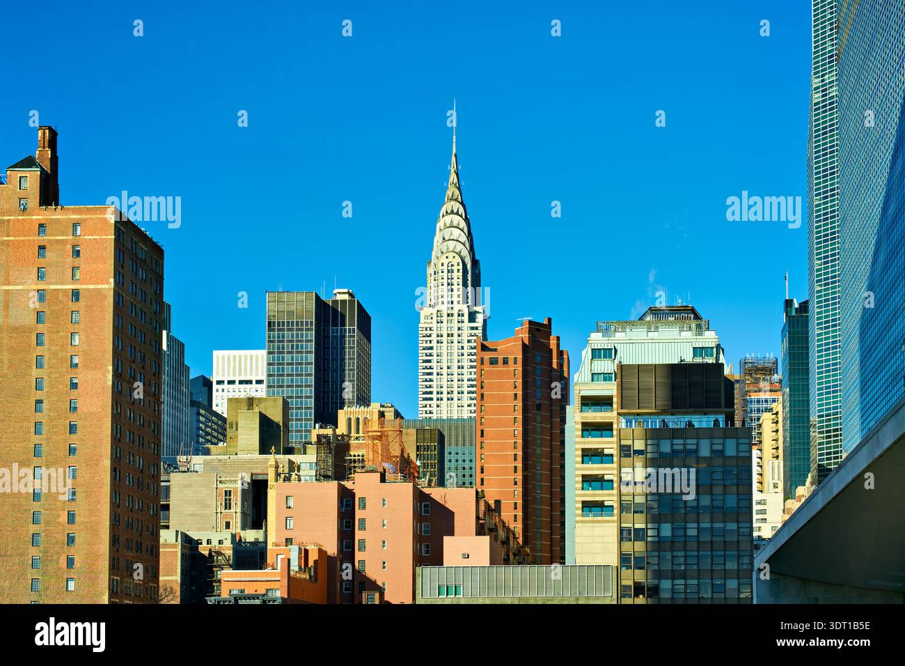 Chrysler Building est visible parmi les différents bâtiments de Manhattan. C'est un jour de ciel bleu clair à New York City avec la lumière du soleil qui brille. Banque D'Images