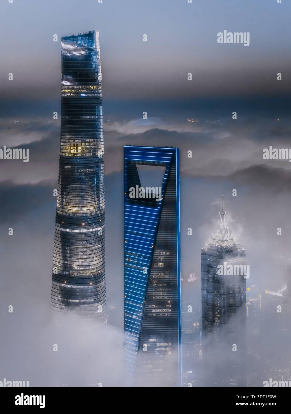 Vue aérienne de gratte-ciel traversant le brouillard épais, leur architecture moderne contrastant avec la brume éthérée, Shanghai, Chine. Banque D'Images