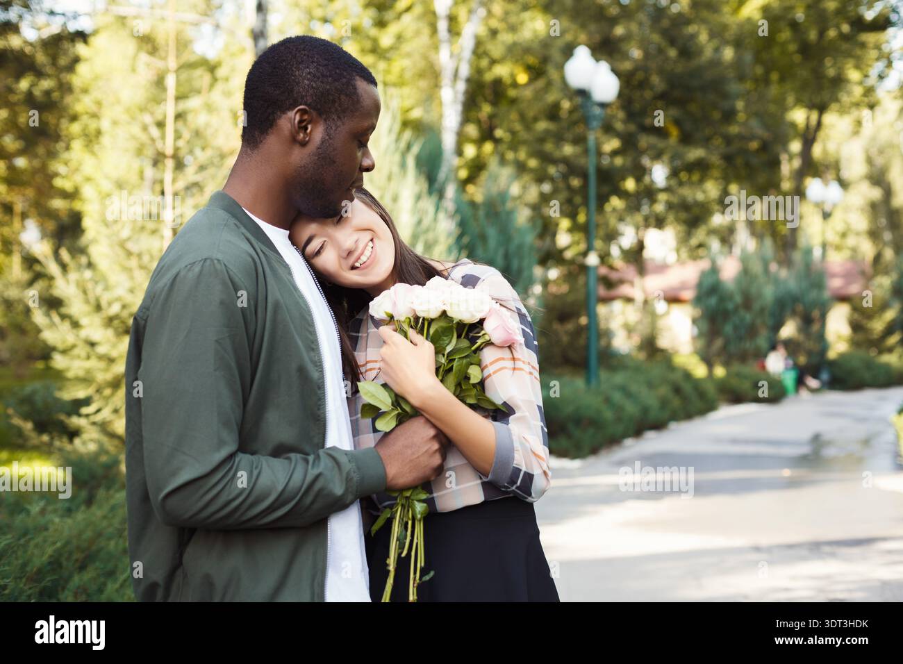 Couple profite d'un moment avec des fleurs dans un parc pendant la journée dans un cadre magnifique Banque D'Images