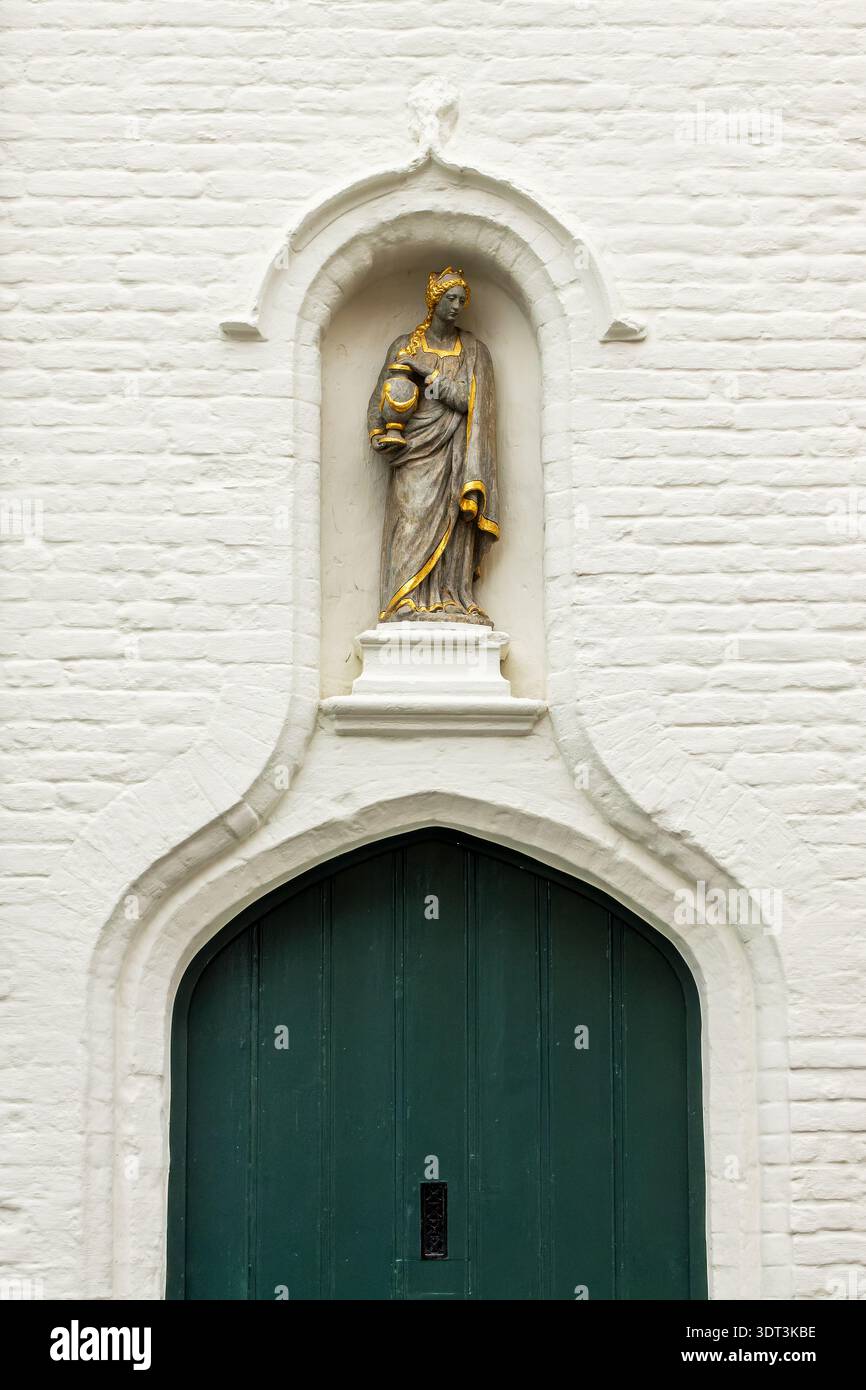 Statue dans une niche au-dessus d'une porte sur la façade d'un bâtiment à Bruges, Belgique Banque D'Images
