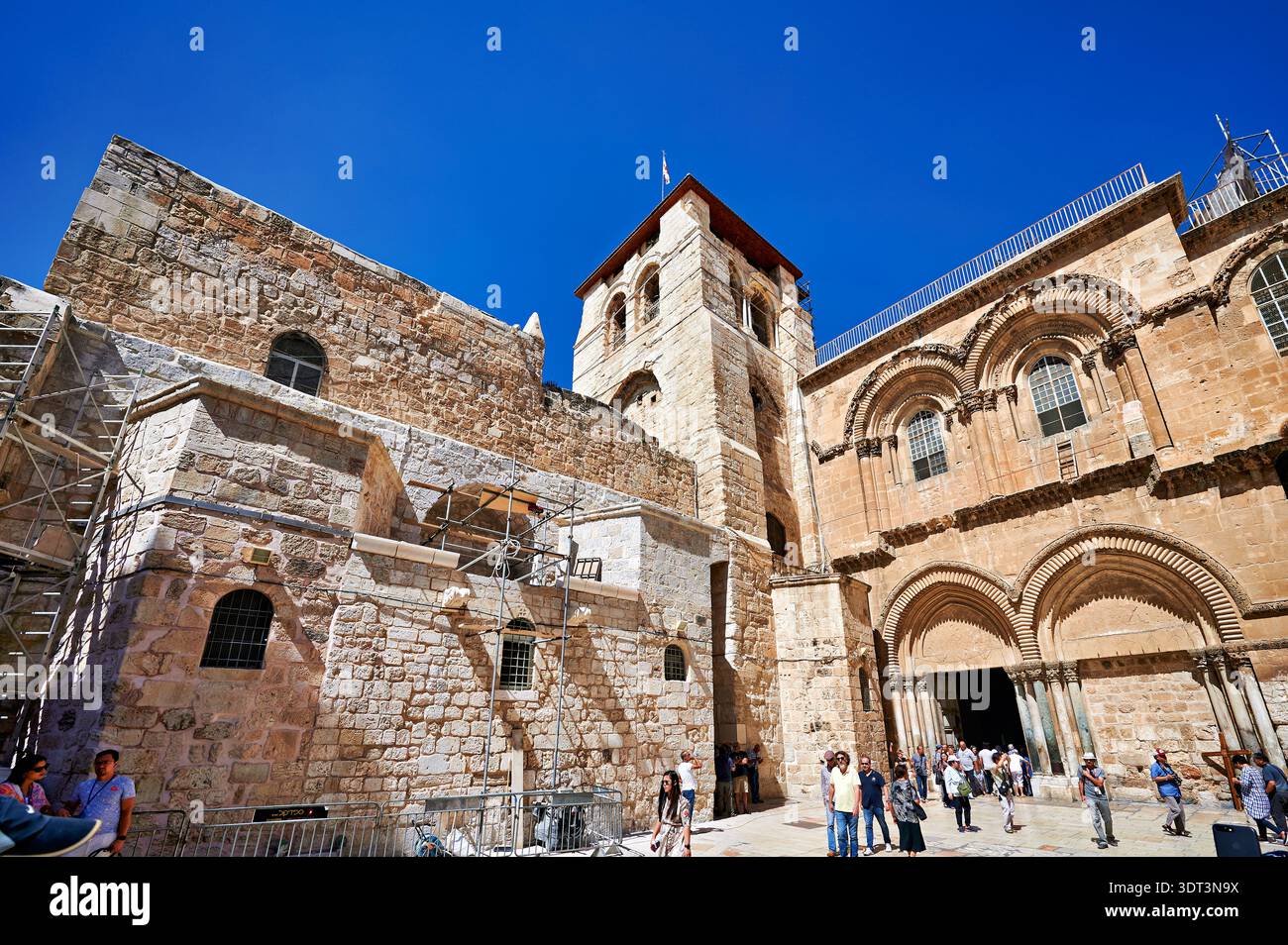 Les visiteurs se rassemblent autour de l'église du Saint-Sépulcre à Jérusalem. Le soleil brille tandis que les gens explorent le site historique et son architecture. Banque D'Images