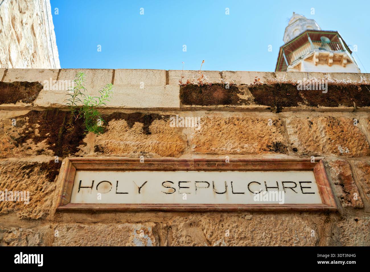 Un panneau marque l'entrée du Saint-Sépulcre à Jérusalem. Les visiteurs explorent ce site historique pendant une journée ensoleillée. Banque D'Images