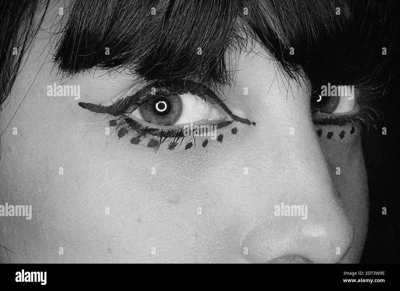 Gros plan des yeux d'une jeune femme avec un look eyeliner graphique Mod inspiré des années 1960 avec une ligne de cils inférieure pointillée distinctive. Banque D'Images