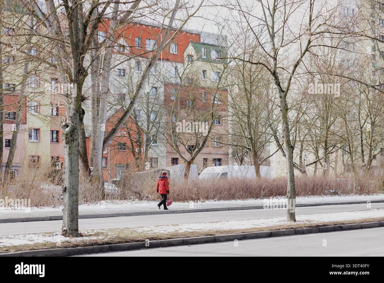 Eine aeltere person mit roter Jacke laeuft alleine entlang einer Strasse, aufgenommen in Berlin, 19.02.2026. Berlin Deutschland *** une personne âgée Banque D'Images