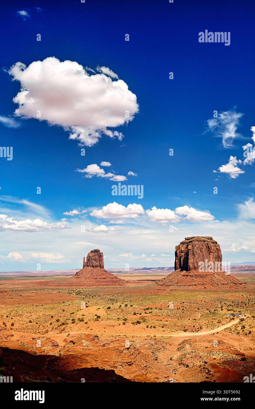 Deux grandes formations rocheuses s'élèvent dans Monument Valley sous un ciel bleu avec des nuages, représentant le paysage unique de la nation Navajo. Banque D'Images