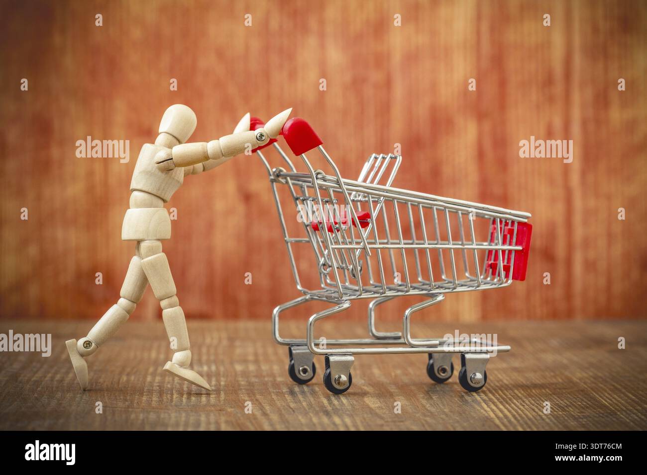 Client avec panier. Allons faire du shopping ! Mannequin en bois poussant un chariot vide Banque D'Images