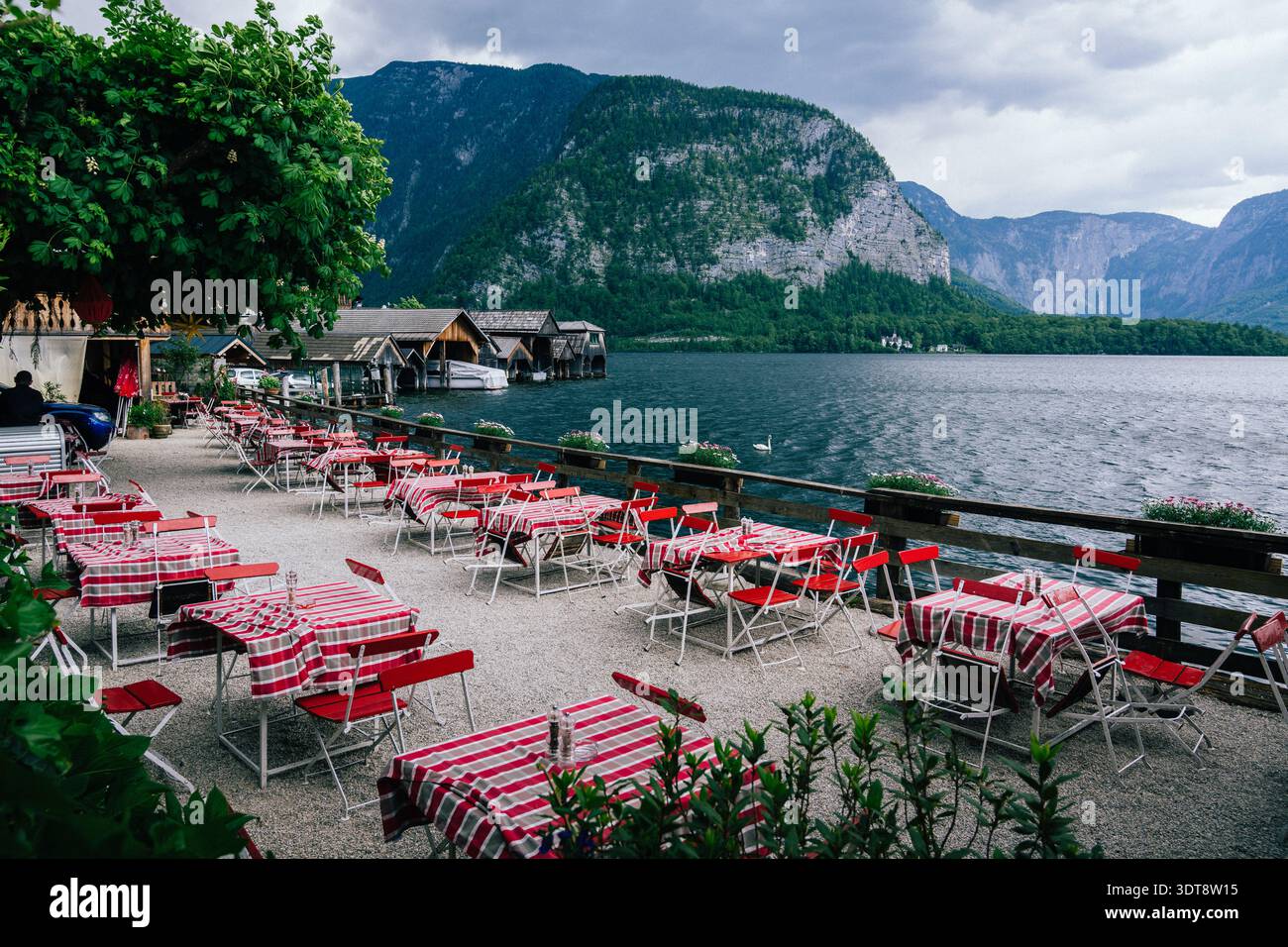 Café pittoresque au bord du lac avec nappes à rayures rouges et blanches et toile de fond de montagne Banque D'Images