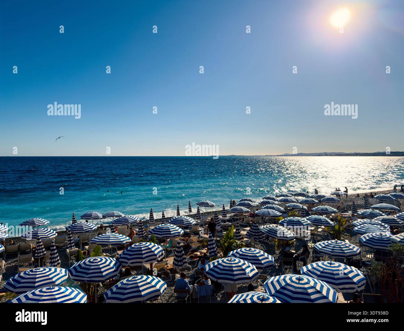Terrasse de bar de plage de luxe avec eau turquoise et parasols bleus au soleil chaud – Nice, Côte d'Azur, France - Image de stock capturée avec un smartphone
