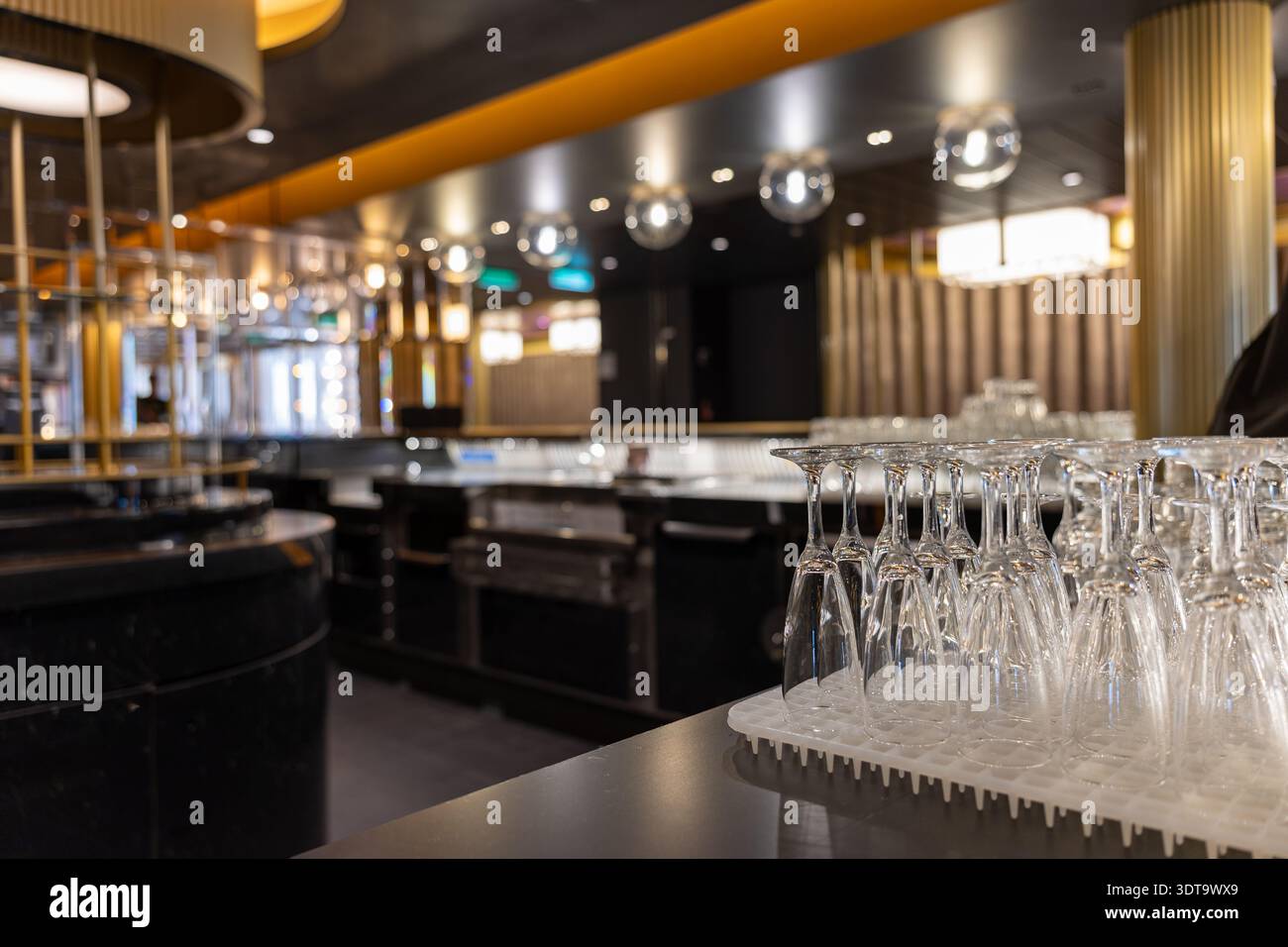 Intérieur élégant du bar avec verres à vin soigneusement disposés sur un comptoir et éclairage d'ambiance chaleureux. Banque D'Images